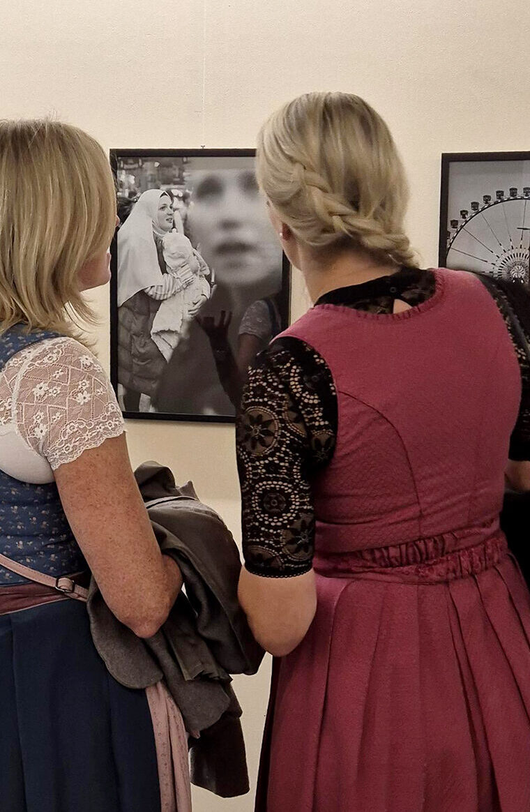 zwei Frauen im Dirndl, von hinten zu sehen, betrachten eine BIld